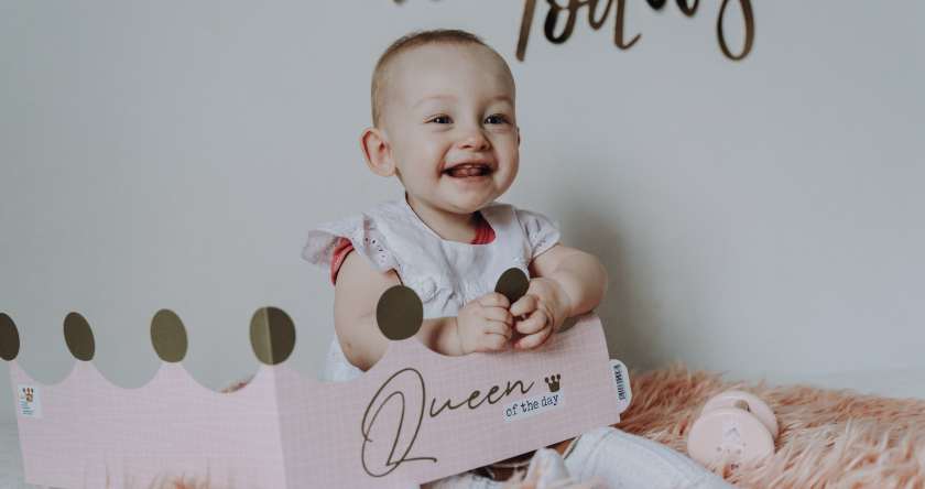 prikaz nasmejane bebe koja sedi na roze ćebencetu