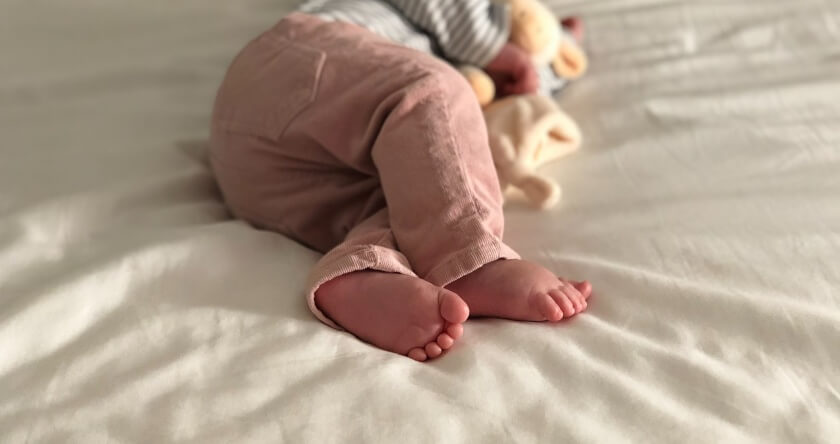 beba sa plišanom igračkom na krevetu